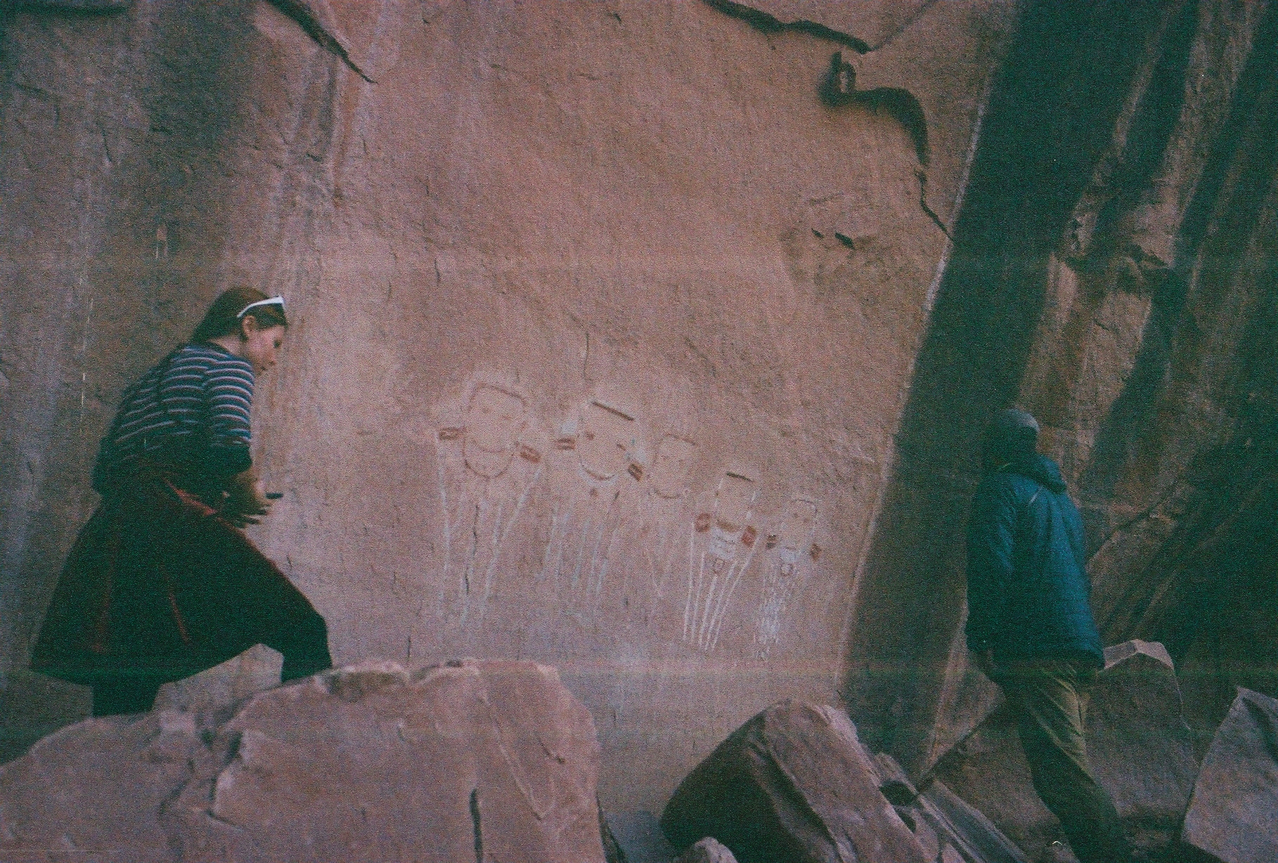 a man and a woman look at rock art painted on a sandstone wall