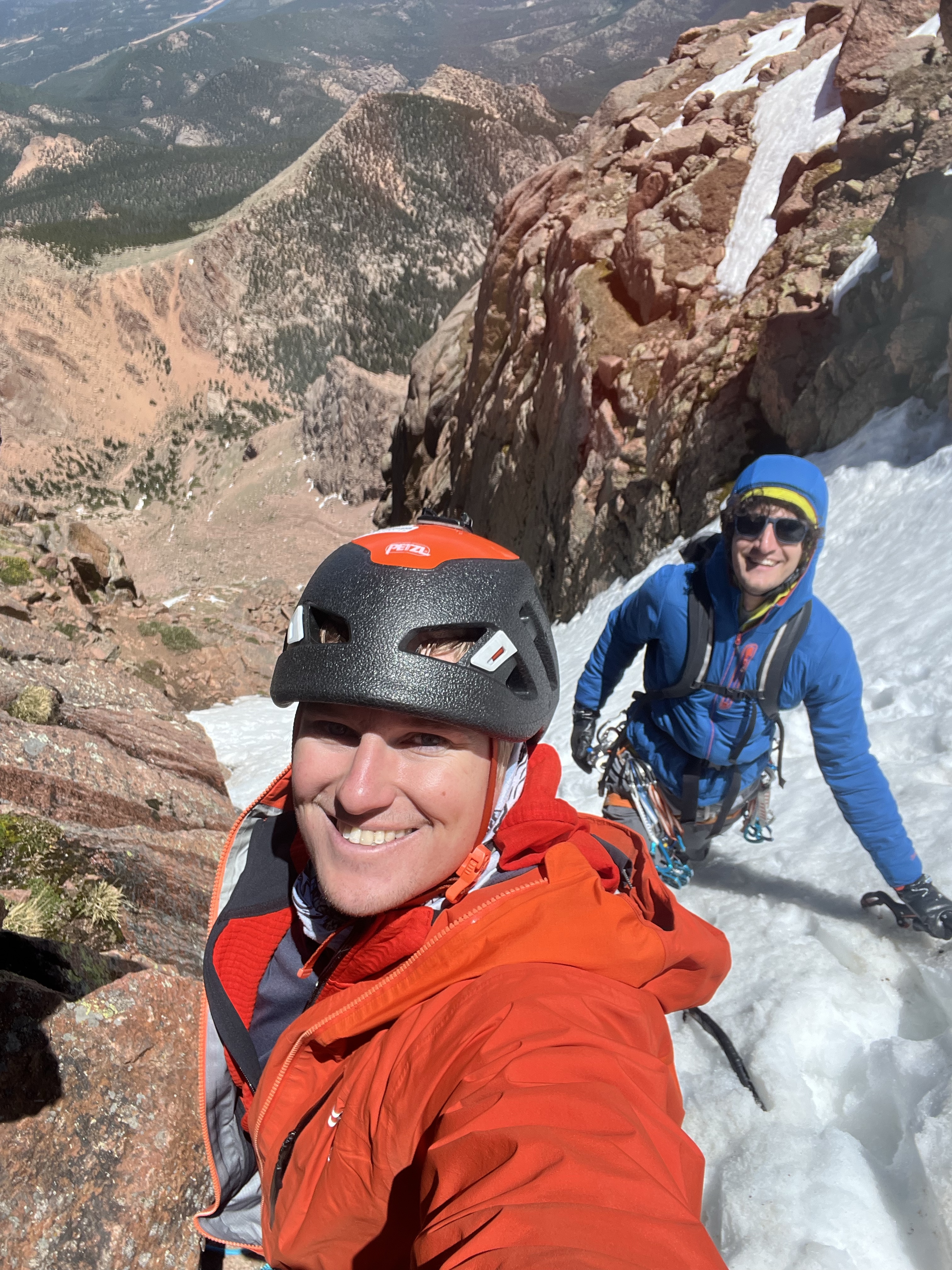 A selfie of two climbers in a snow gully. It is sunny, and they are climbing unroped on moderately steep terrain. The climber in the back wears the black Showa Temres 282-02 gloves for ice climbing. Both men smile at the camera.